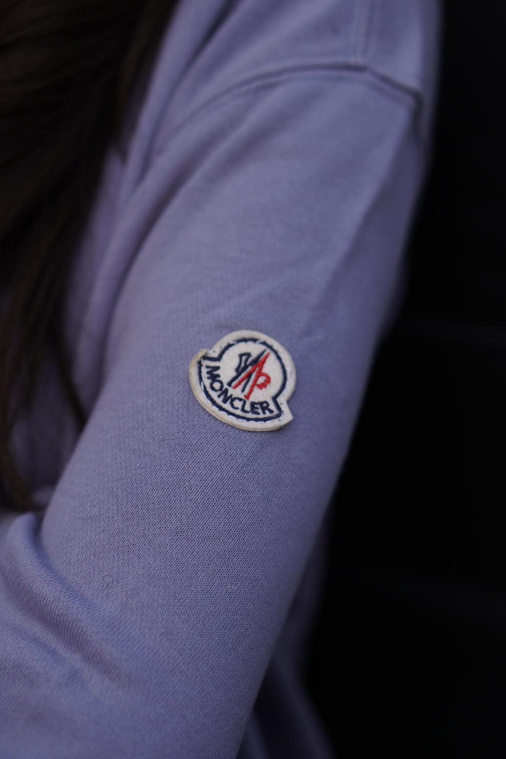 Close-up of a blue shirt with a logo on the sleeve against a dark background